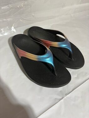 OOFOS Women's Black Flip Flop Sandals with Blue, Gold, and Pink Gradient Straps